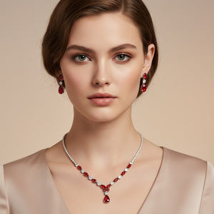 Model wearing red and clear crystal dainty necklace set on silver with spaced crystal accents, a delicate center drop, and matching drop earrings.