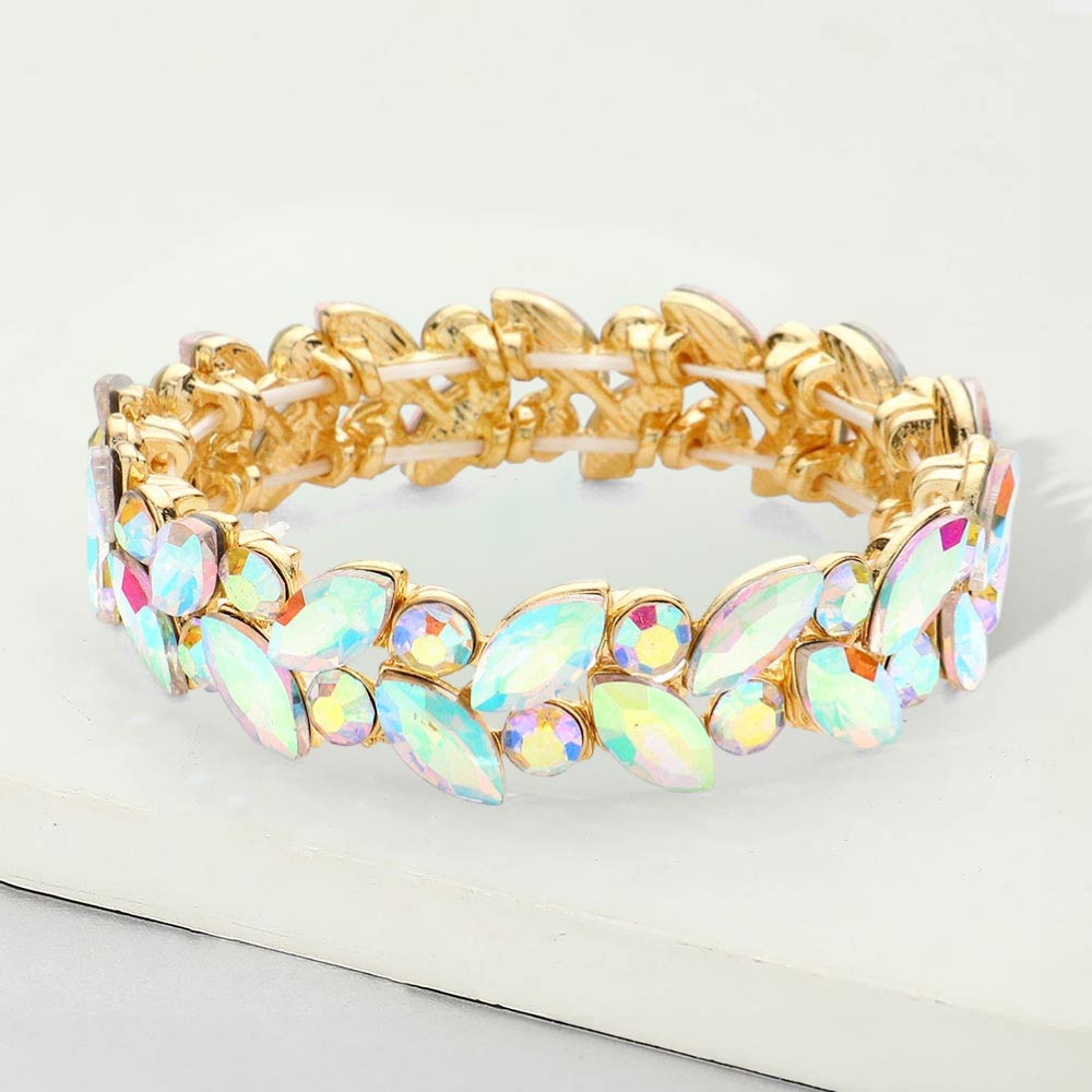 AB marquise and round stone cluster stretch bracelet on gold with iridescent stones on a white marble background