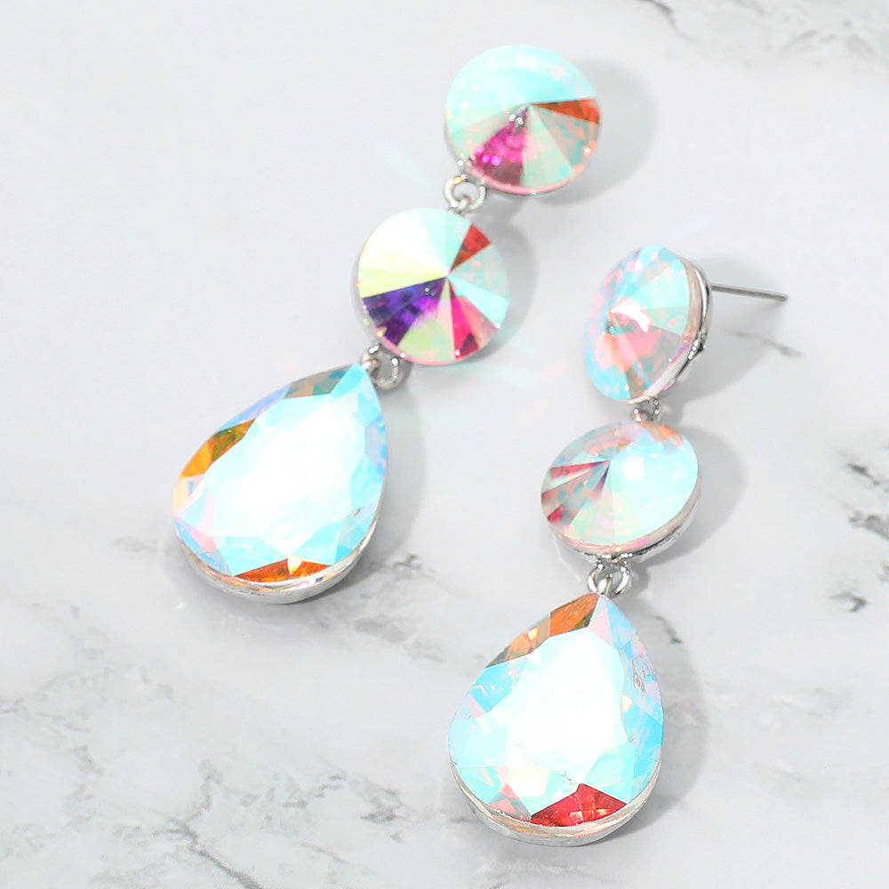 AB round and teardrop cluster dangle earrings on silver with iridescent sparkle for weddings or interviews on a marble background