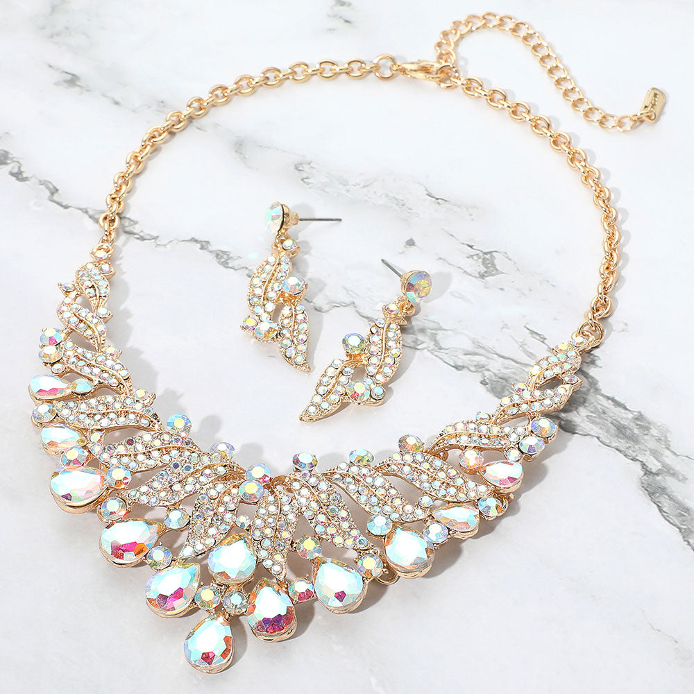 AB teardrop leaf crystal collar necklace set on gold with matching earrings, iridescent statement jewelry for prom and evening wear on a marble background