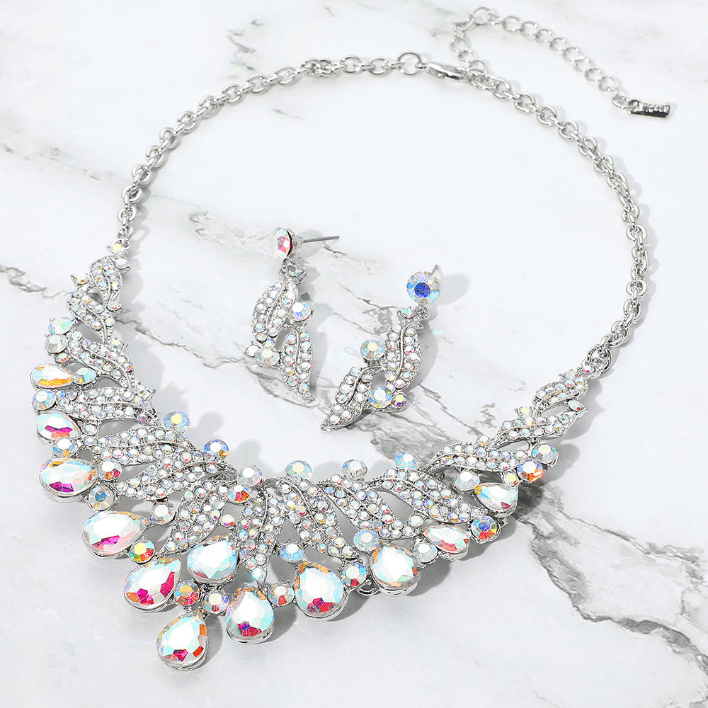 AB teardrop leaf crystal collar necklace set on silver with matching earrings, iridescent statement jewelry for prom and evening wear on a marble background