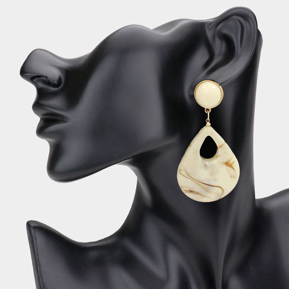 Ivory resin teardrop cutout dangle earrings on a black mannequin ear on a white background— bold modern 3.25" fashion statement jewelry.