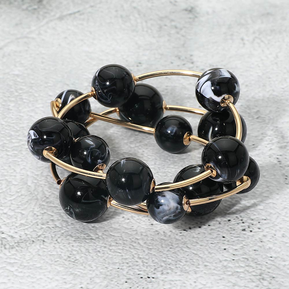 Black chunky ball 3-piece stretch bracelet set on gold displayed on a light textured background.