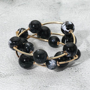 Black chunky ball 3-piece stretch bracelet set on gold displayed on a light textured background.