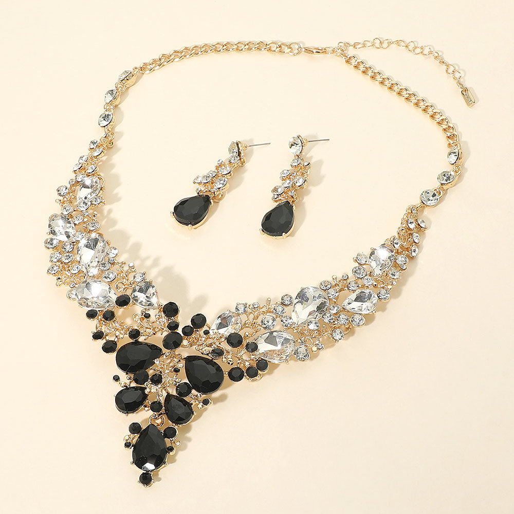 Black and clear teardrop crystal jewelry set on gold featuring statement necklace and matching drop earrings on beige background