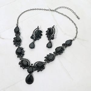 Black teardrop formal necklace and matching earrings set on silver displayed on a white background.