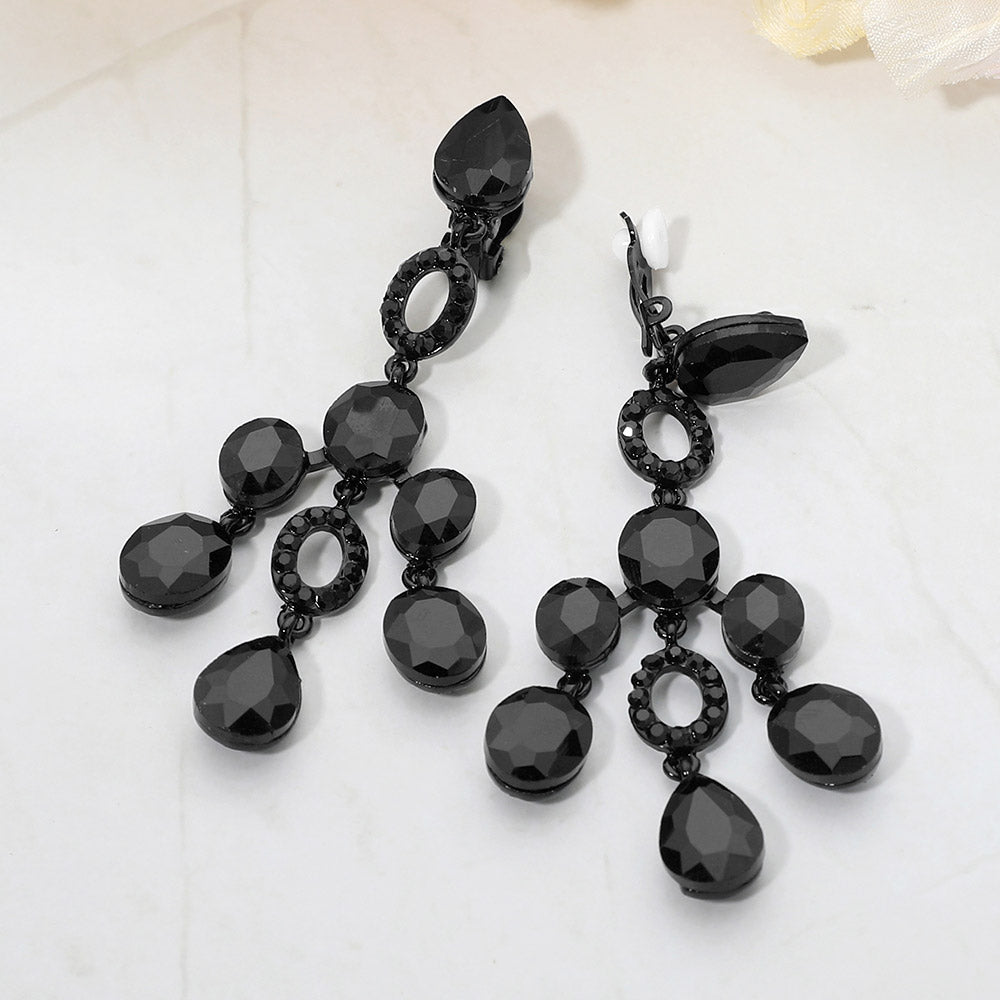 Black faceted chandelier clip-on earrings with cascading dangle stones on a marble background