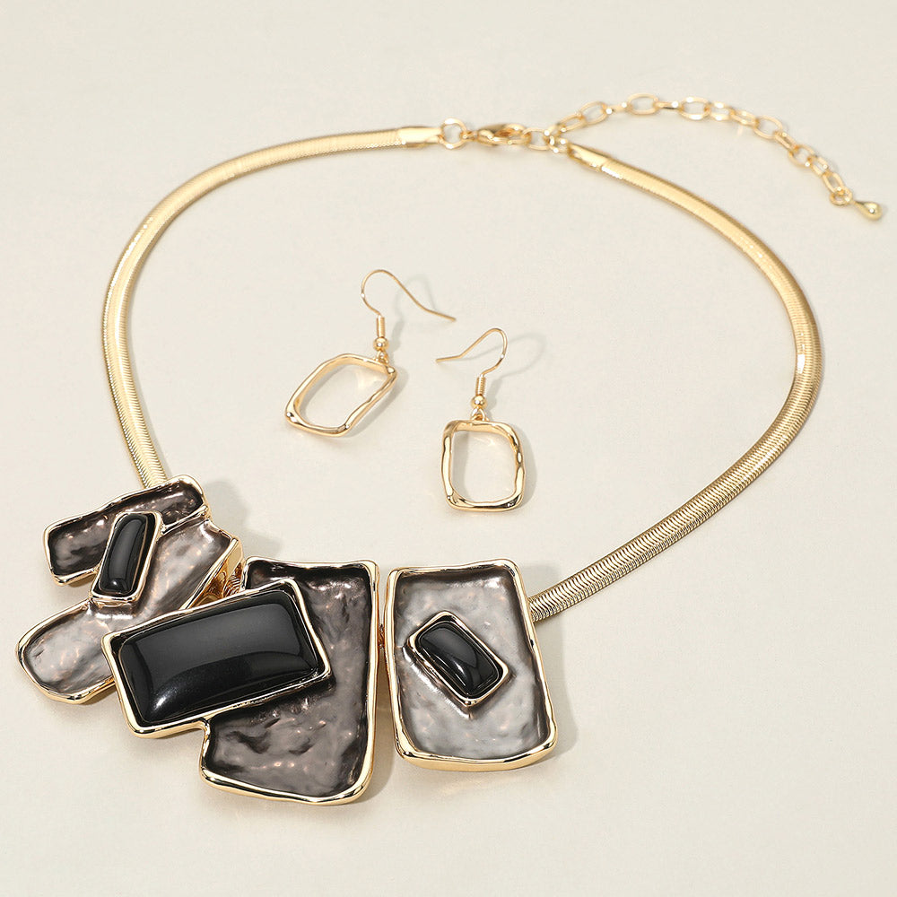 Black geometric enamel beaded necklace set with earrings for evening or pageant events. It is on a ivory background.