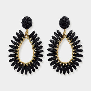 A pair of black and gold statement dangle earrings featuring a textured black rose stud and a teardrop-shaped dangle with black petal-like beads and gold accents, set against a light gray background.