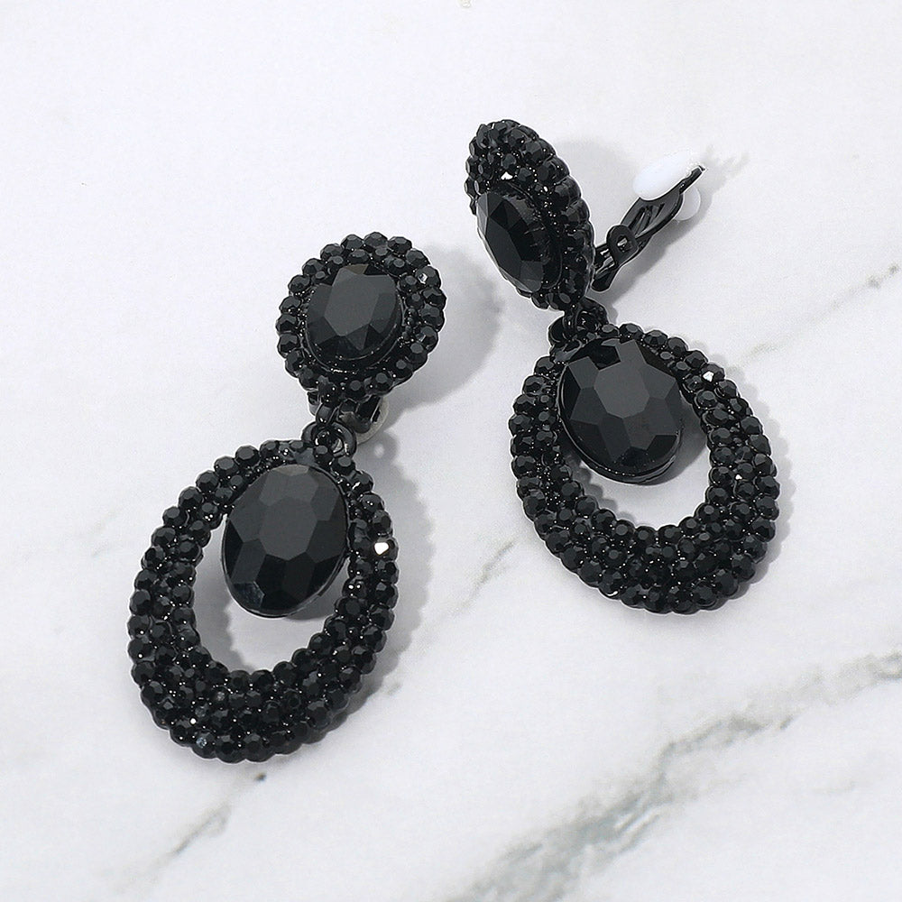 Black oval double-halo crystal clip-on earrings on a white marble background — 2.1" statement drops for evening or pageant glam.