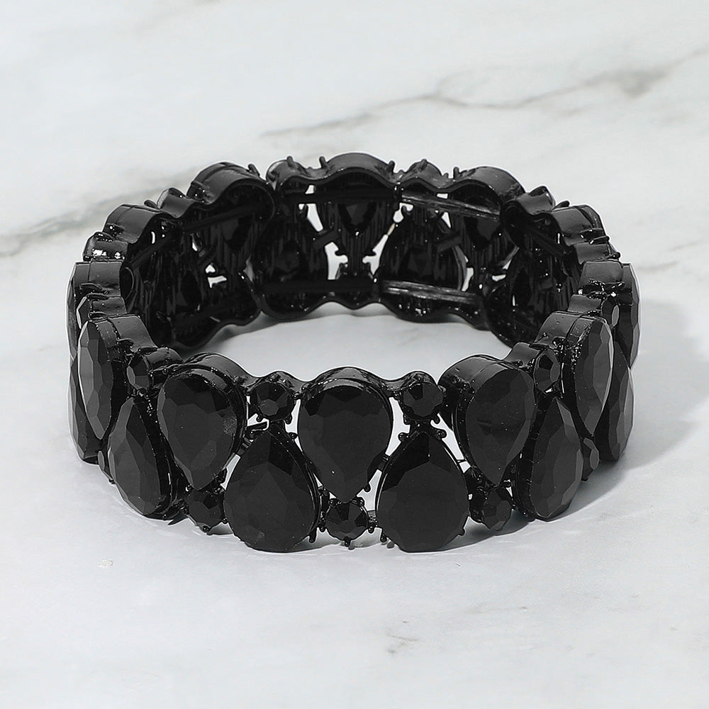 Black teardrop and round stone cluster stretch bracelet on white marble background