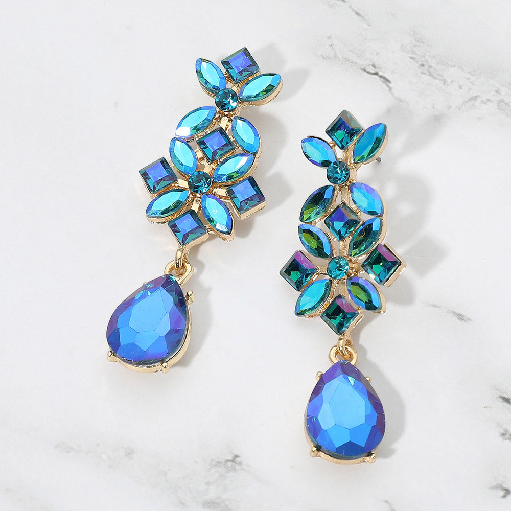 Blue AB crystal floral teardrop earrings on gold-tone metal, featuring iridescent clusters of marquise, square, and round stones above large faceted teardrop drops. Each earring measures approximately 0.8 inches wide by 2.5 inches long. Displayed on a white marble surface with gray veining.