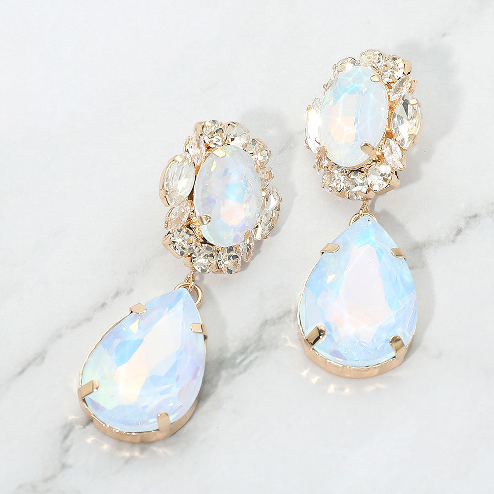 Light blue AB oval and teardrop earrings with clear crystal accents on gold on a white marble background