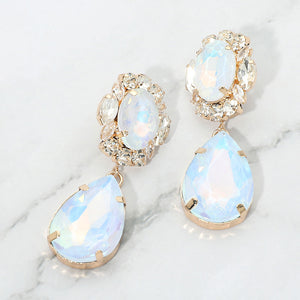 Light blue AB oval and teardrop earrings with clear crystal accents on gold on a white marble background