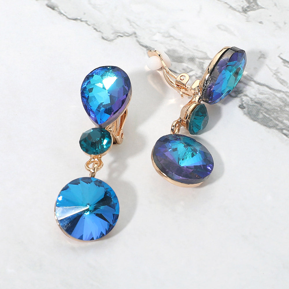 Blue AB round crystal drop clip-on earrings on gold with iridescent stones on white marble background