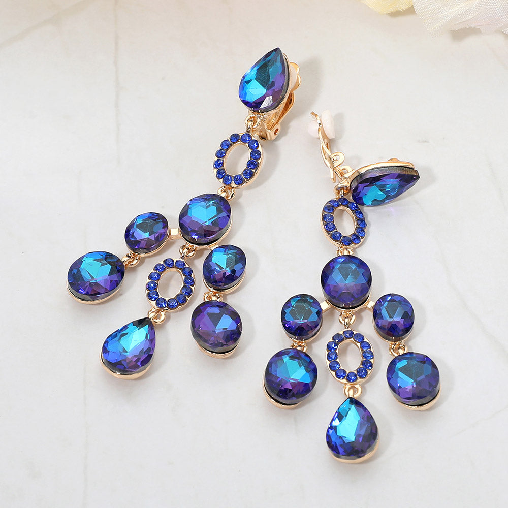Blue faceted chandelier clip-on earrings with cascading dangle stones and gold-tone setting on a marble background