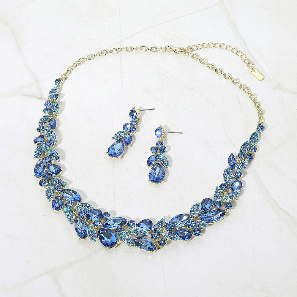 Blue Sapphire marquise and teardrop crystal cluster formal necklace set on gold with matching earrings on white marble background