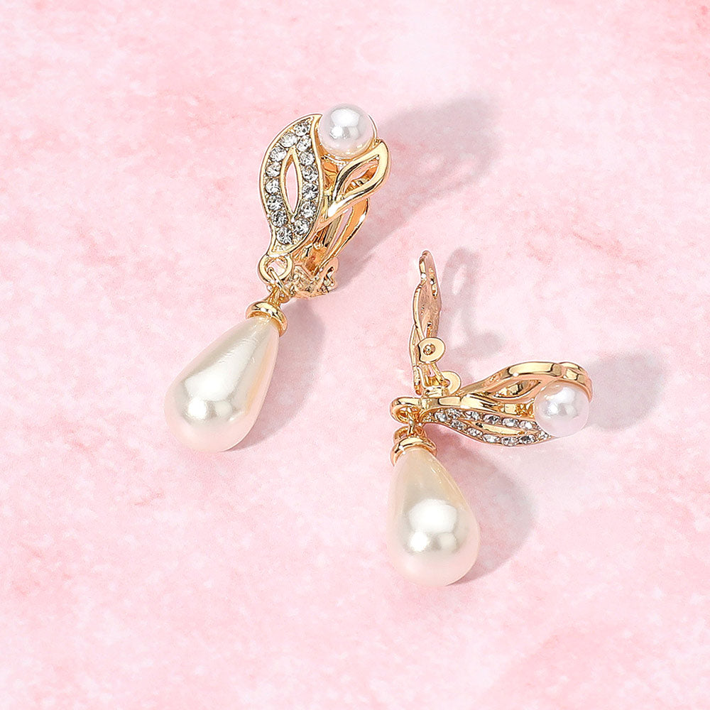 Bridal pearl and rhinestone teardrop clip-on earrings on gold for wedding, prom, or mother-of-the-bride style on a pink background