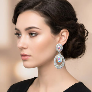 AB oval double-halo crystal clip-on earrings on silver on a pretty lady on a blurred peach background — 2.1" silver statement drops for evening or pageant glam.