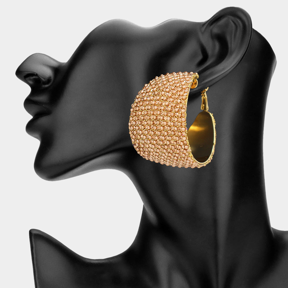Champagne gold stone bling pavé crystal wide hoop earrings on gold-tone metal with dense faceted rhinestone coverage and omega backs, displayed on a black mannequin profile.