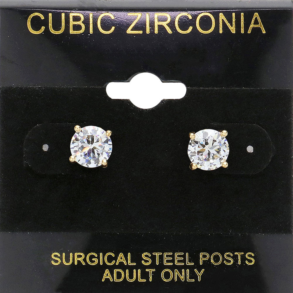 Classic round clear crystal stud earrings in a gold finish with prong settings and surgical steel posts, displayed on a black jewelry card.