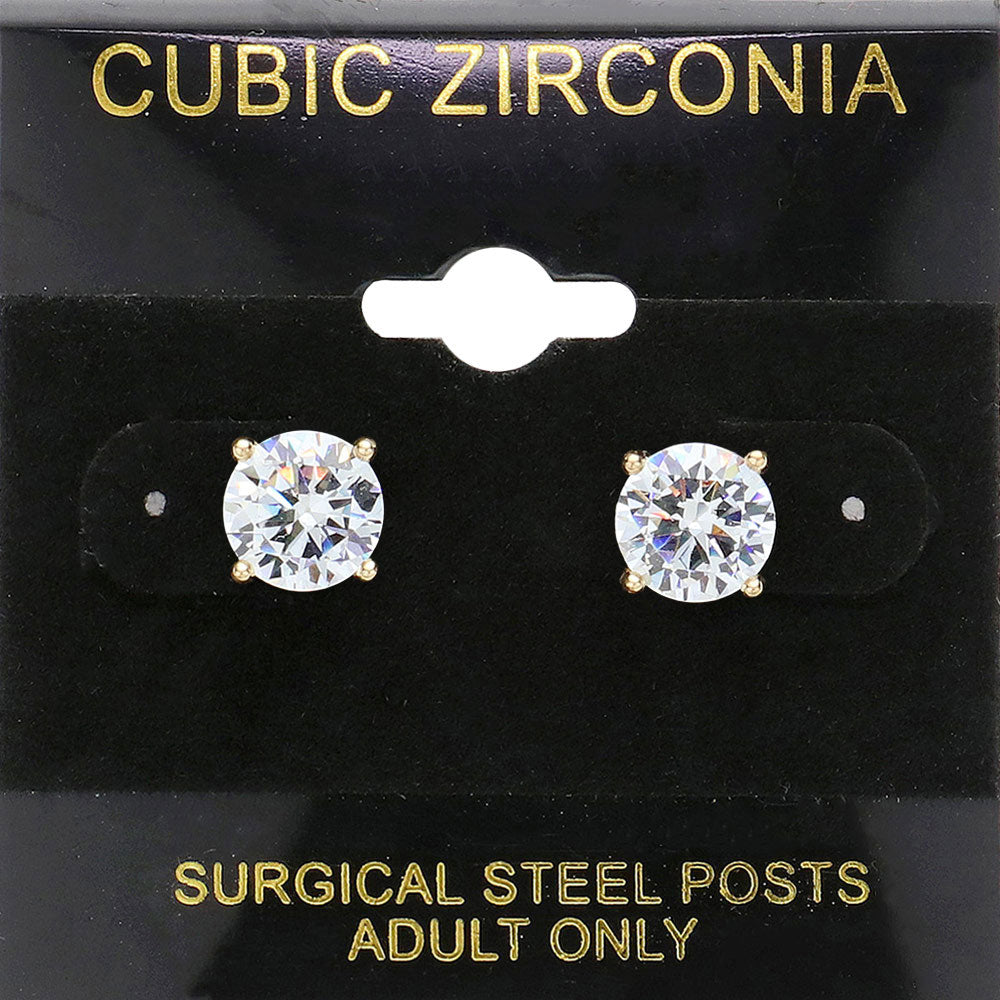 Classic round clear crystal stud earrings in a gold finish with prong settings and surgical steel posts, displayed on a black jewelry card.