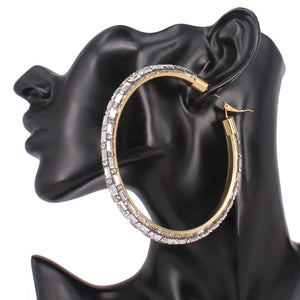 Oversized clear baguette rhinestone hoop earrings on gold with omega back 3.5 inch diameter shown on a black mannequin ear