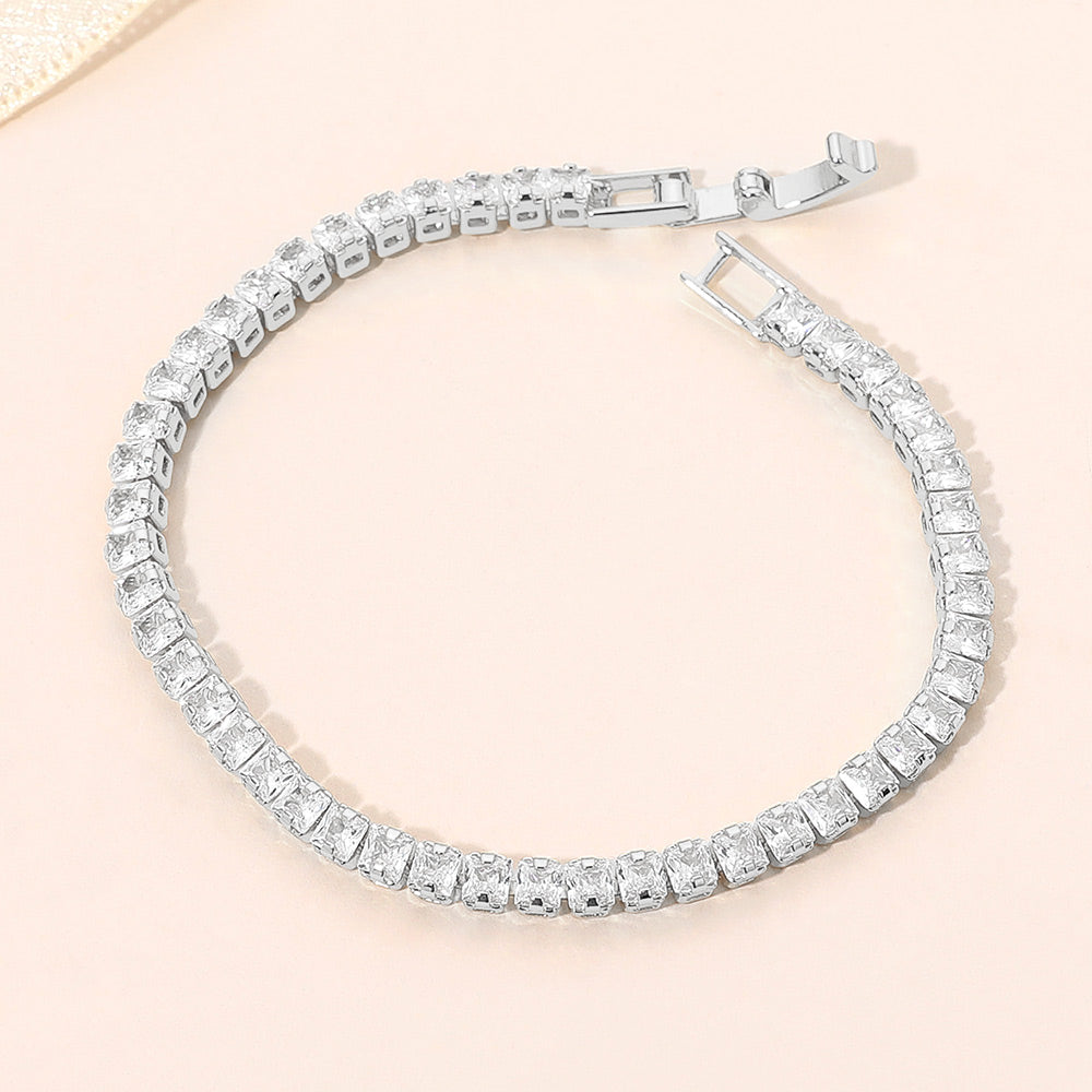 Clear crystal square tennis bracelet in a silver finish featuring a continuous row of square-cut clear crystals with a fold-over clasp, displayed on a light jewelry background.