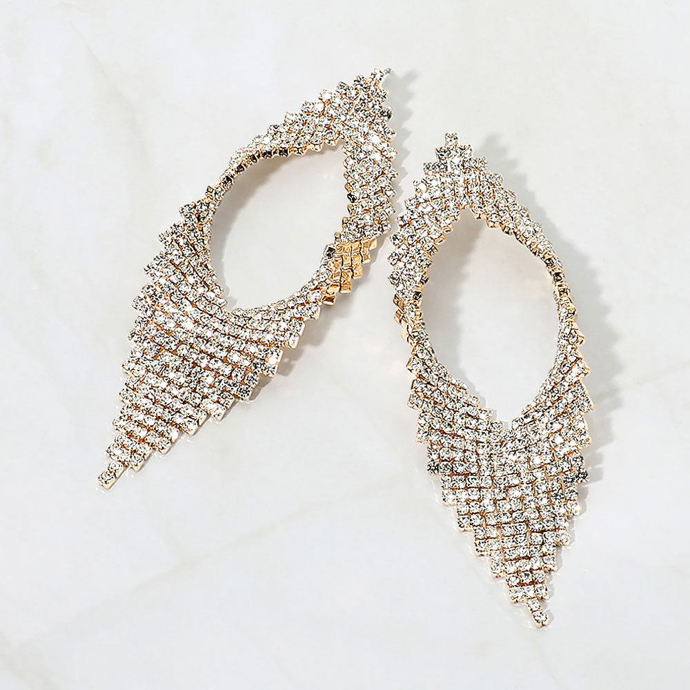 Clear crystal abstract layered statement earrings on gold displayed on a white background.