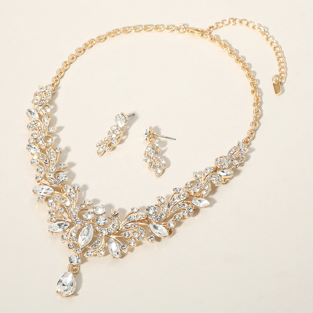 Clear crystal stone cluster prom necklace set on gold with matching earrings on a cream background