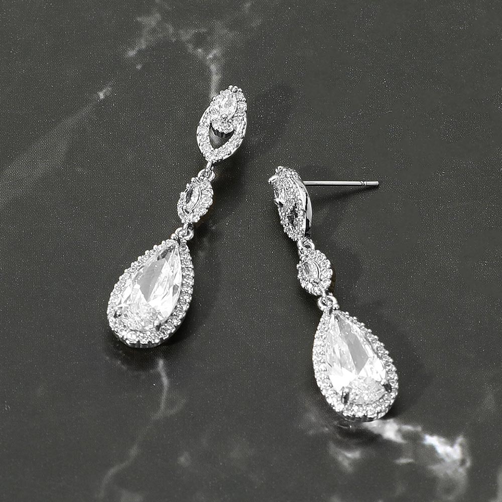 Pair of silver teardrop earrings on a dark marble surface