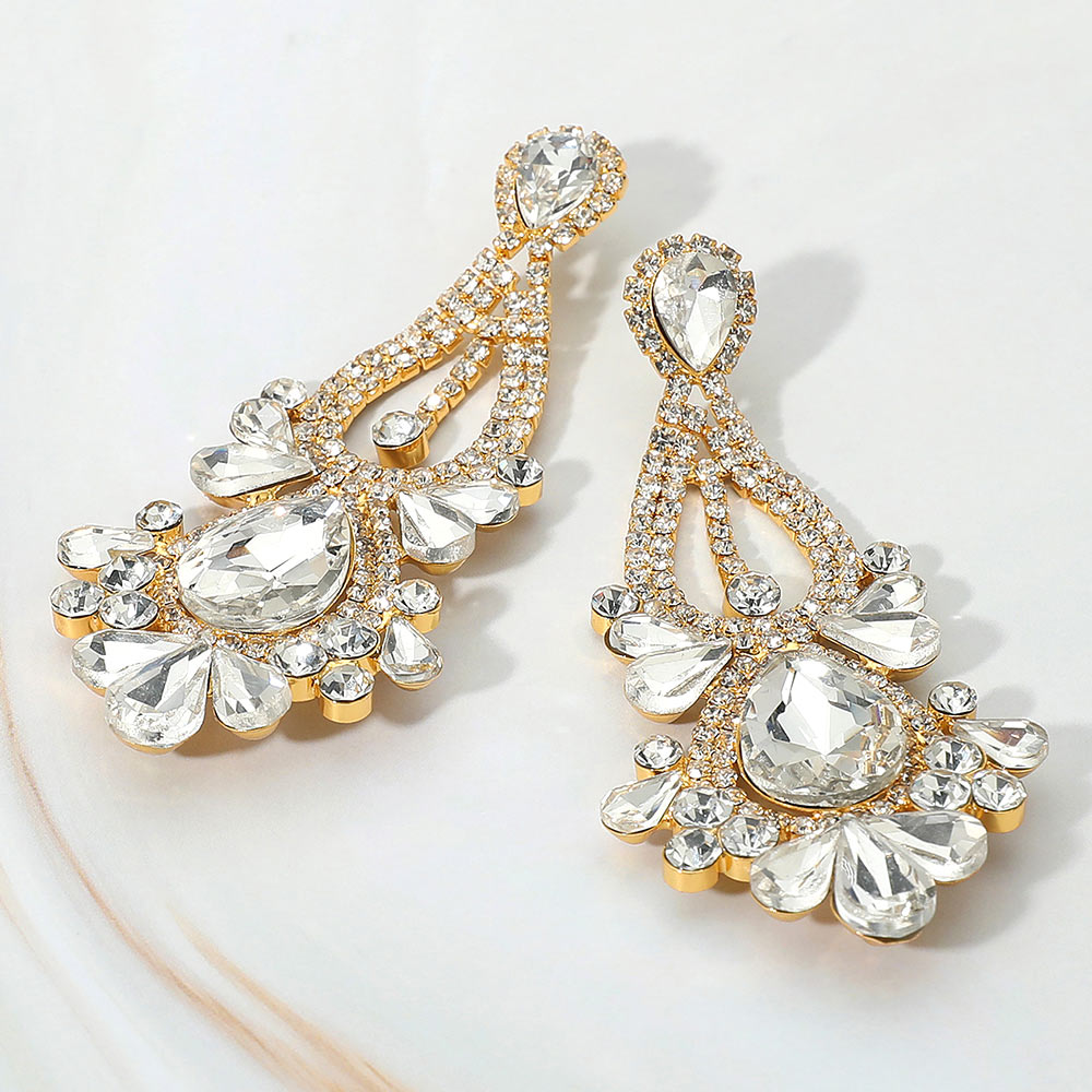 Clear chandelier teardrop statement earrings on gold with stone cluster design for bridal, prom, or evening wear on a light background.