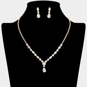 Clear crystal dainty necklace set on gold with spaced crystal accents, a delicate center drop, and matching drop earrings, displayed on a black jewelry bust.