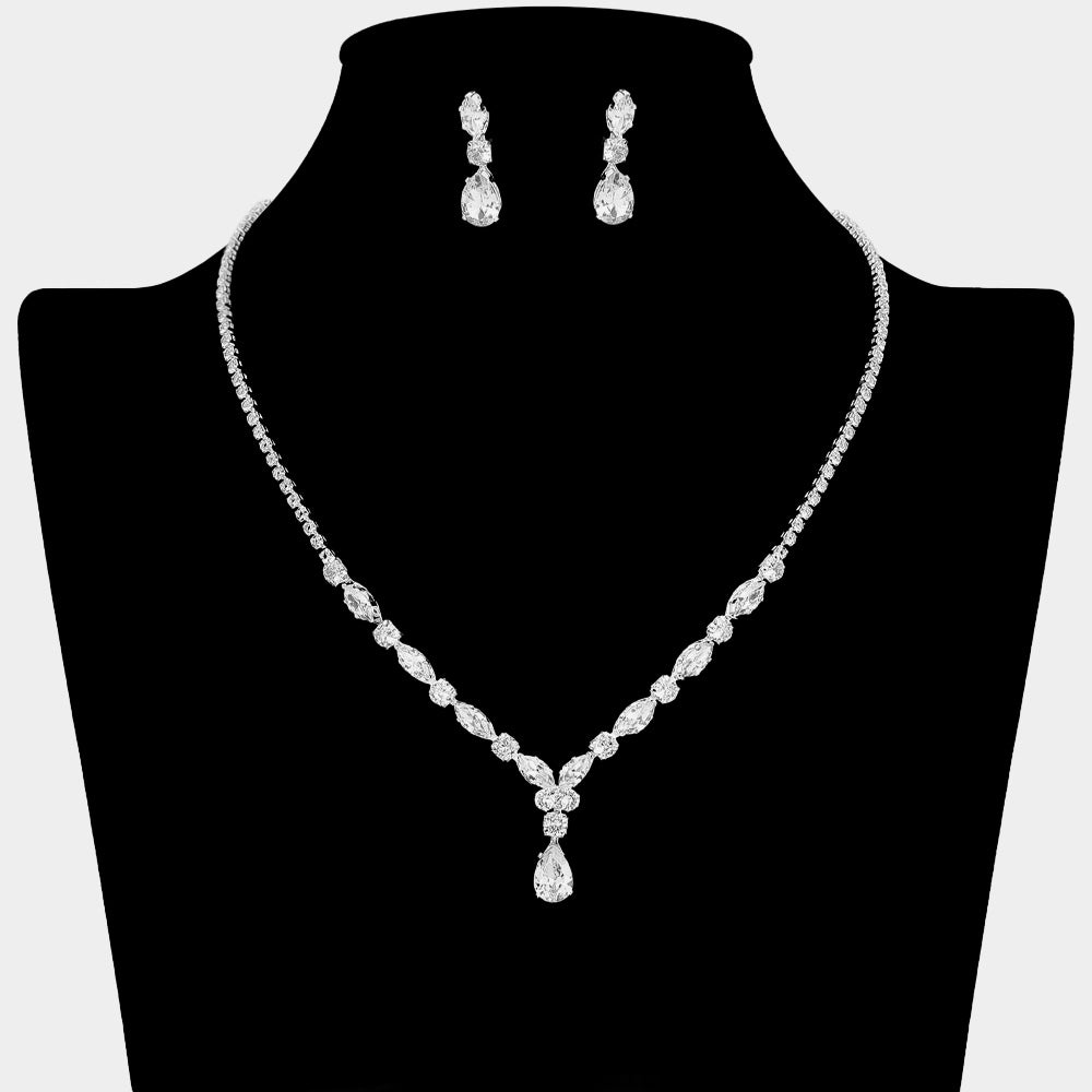 Clear crystal dainty necklace set on silver with spaced crystal accents, a delicate center drop, and matching drop earrings, displayed on a black jewelry bust.