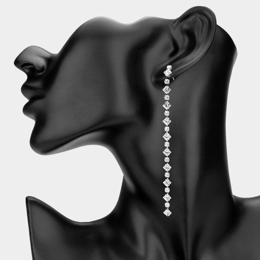 Long geometric crystal link drop earrings in a silver finish featuring a vertical row of clear crystals, displayed on a black model ear.