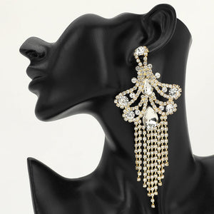 A large ornate Clear Crystal statement earring on gold with cascading bead fringe and clear crystal accents on a black earring mannequin.
