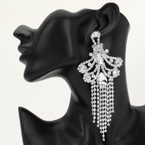 A large ornate Clear Crystal statement earring on silver with cascading bead fringe and clear crystal accents on a black earring mannequin.