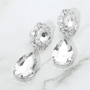 Clear crystal teardrop dangle earrings on silver with oval crystal accents on a white marble background