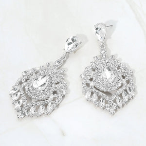Clear crystal teardrop chandelier statement pageant earrings on silver with an ornate layered crystal design, displayed on a white marble background.