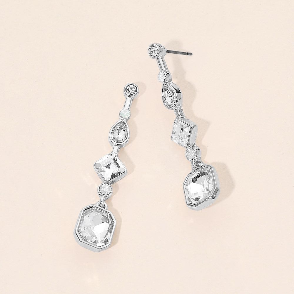 Clear geometric crystal link drop earrings on silver with faceted stones on a beige background.