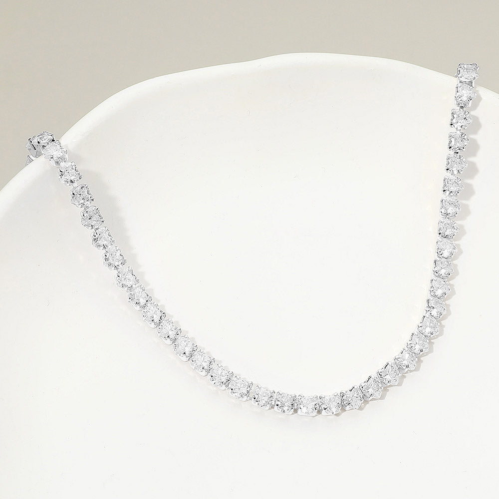 Clear crystal heart tennis necklace in a silver finish featuring a continuous row of heart-shaped clear crystals, displayed on a white jewelry display.