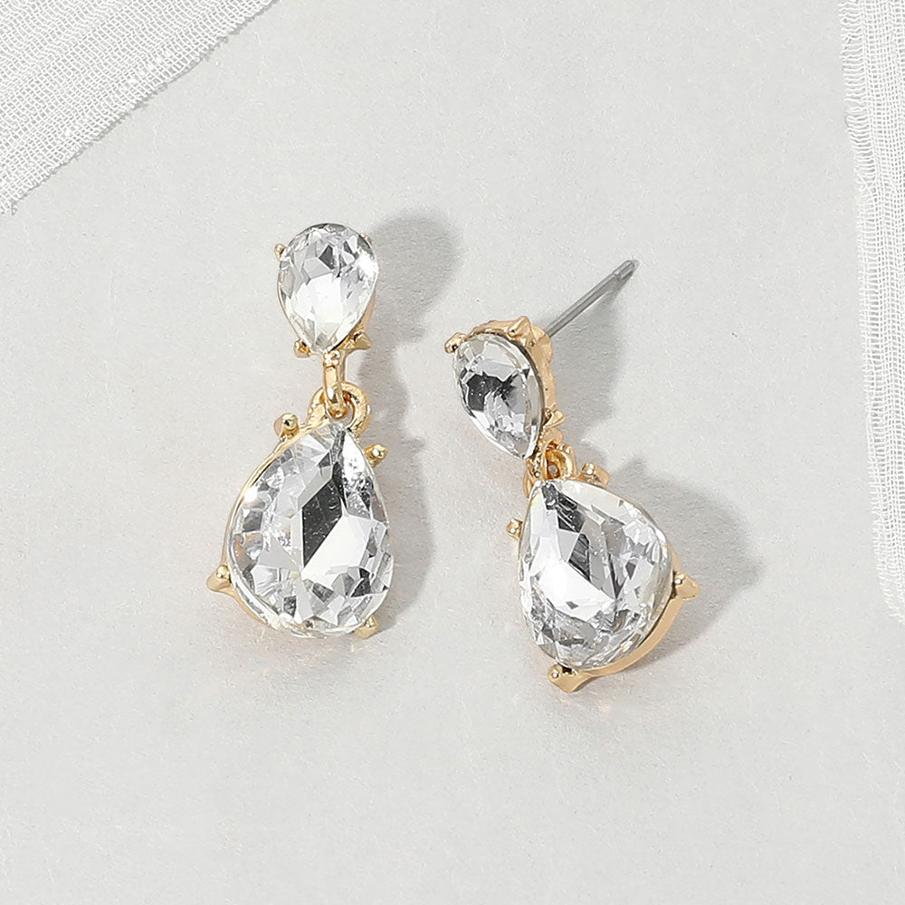 Double teardrop dangle earrings with clear crystals on gold, measuring 1 inch long by 0.4 inch wide, featuring smaller faceted teardrops above larger drops, displayed on a white textured surface.