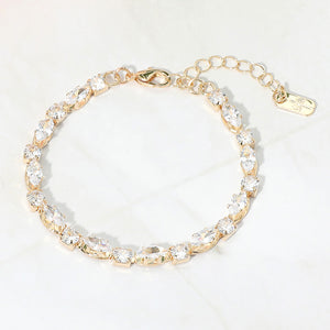 Clear marquise crystal prom bracelet on gold on white marble background