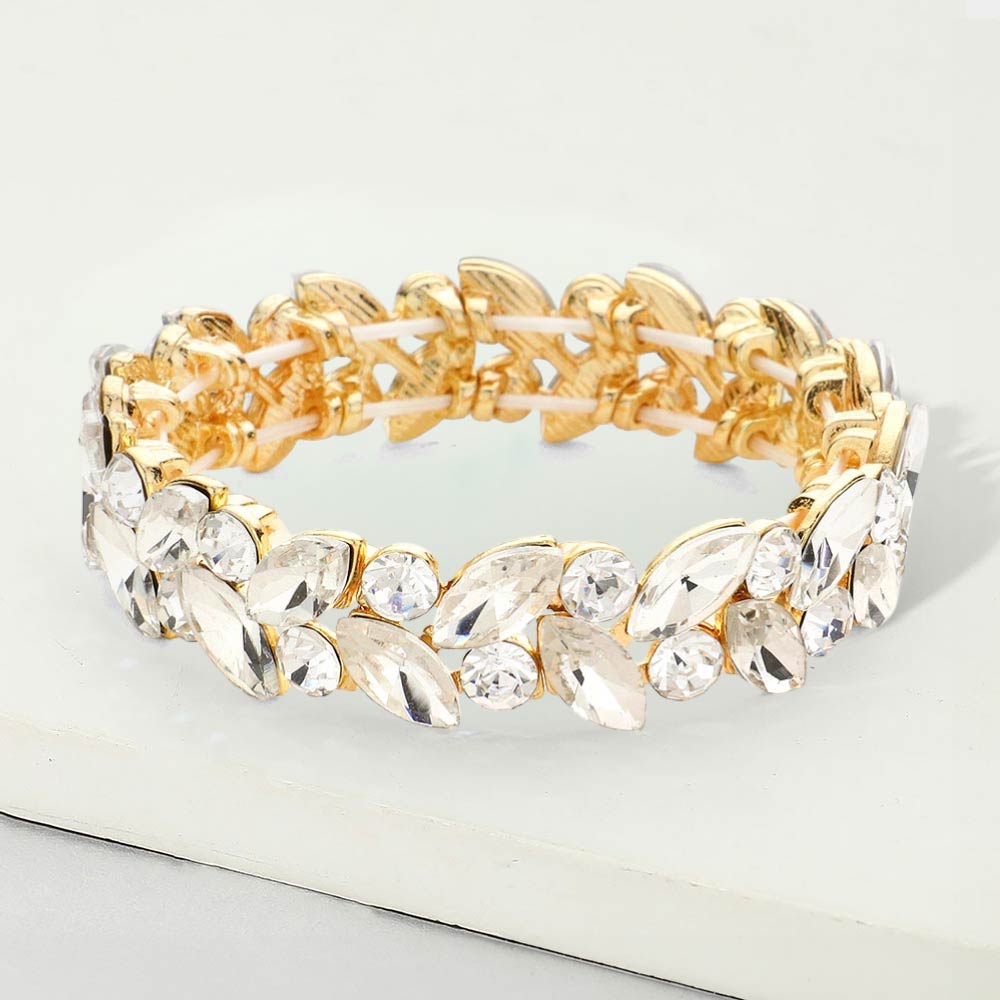 Clear marquise and round stone cluster stretch bracelet on gold on a white marble background