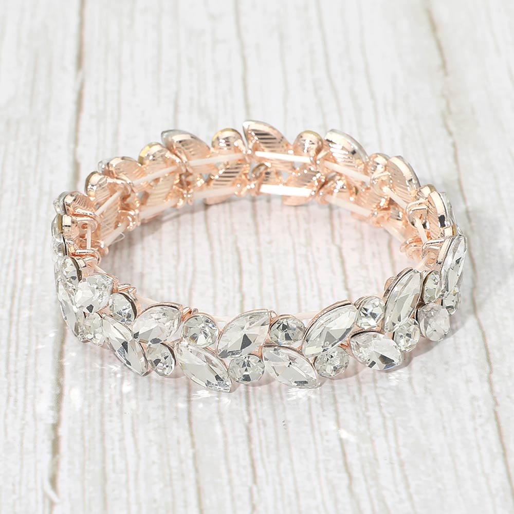 Clear marquise and round stone cluster stretch bracelet on rose gold on a light white wood background