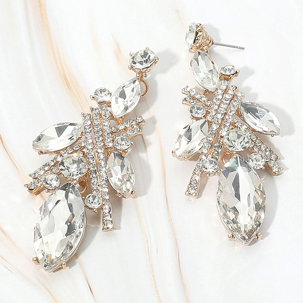 Clear marquise stone and rhinestone cluster drop earrings on gold on white marble background