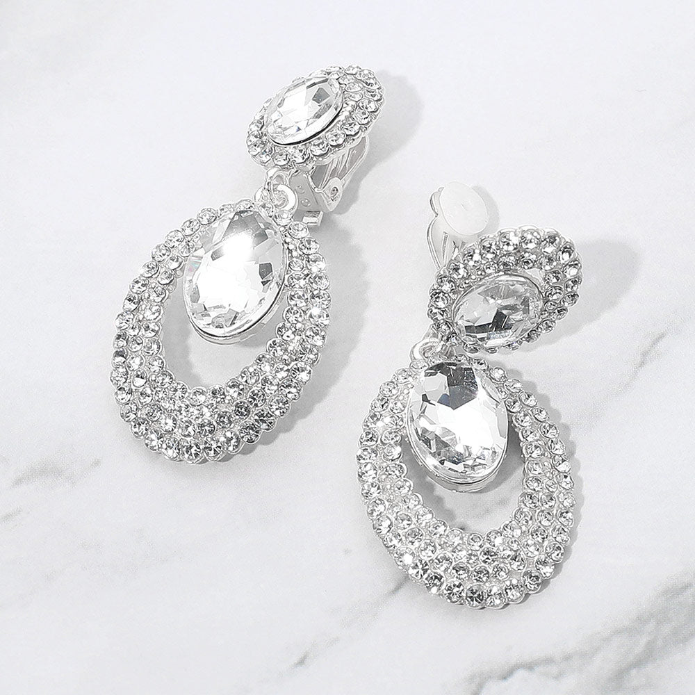 Clear oval double-halo crystal clip-on earrings on silver on a white marble background — 2.1" silver statement drops for evening or pageant glam.