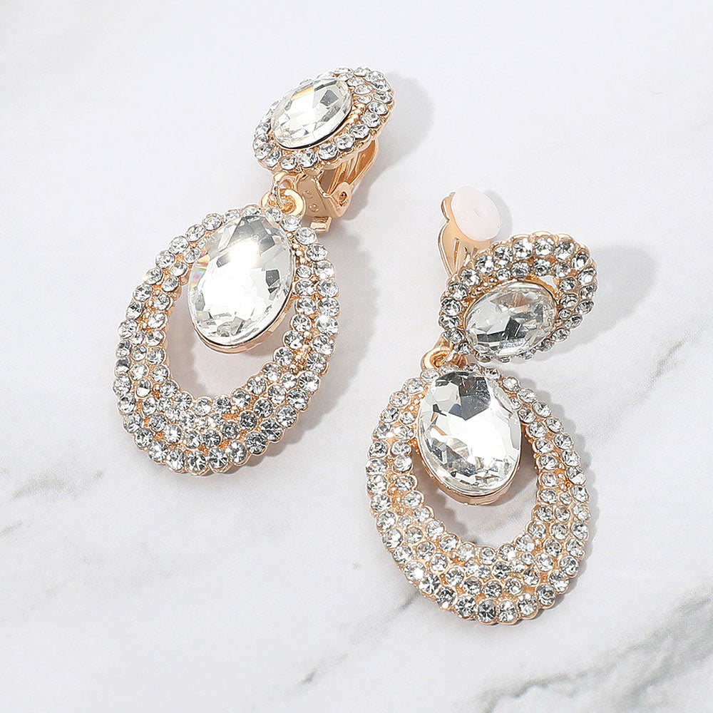 Clear oval double-halo crystal clip-on earrings on gold on a white marble background — 2.1" statement drops for evening or pageant glam.