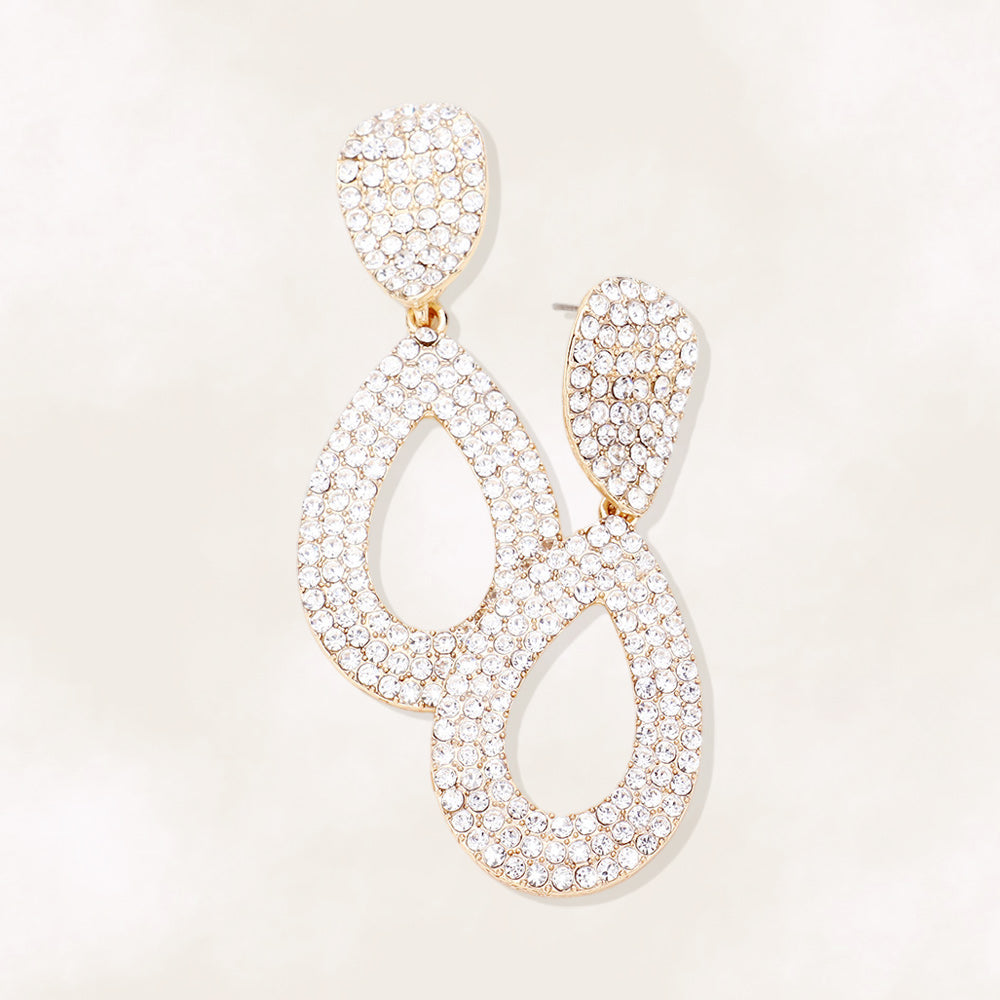 Clear rhinestone pavé cut out teardrop pageant earrings on gold with brilliant crystal sparkle on beige background.