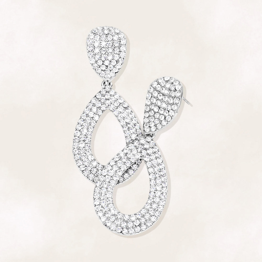 Clear rhinestone pavé cut out teardrop pageant and formal earrings on silver on a beige background